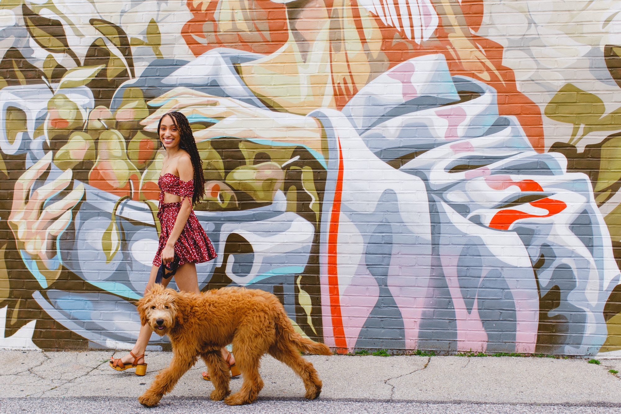 Alize and her dog Frank walk in front of a mural