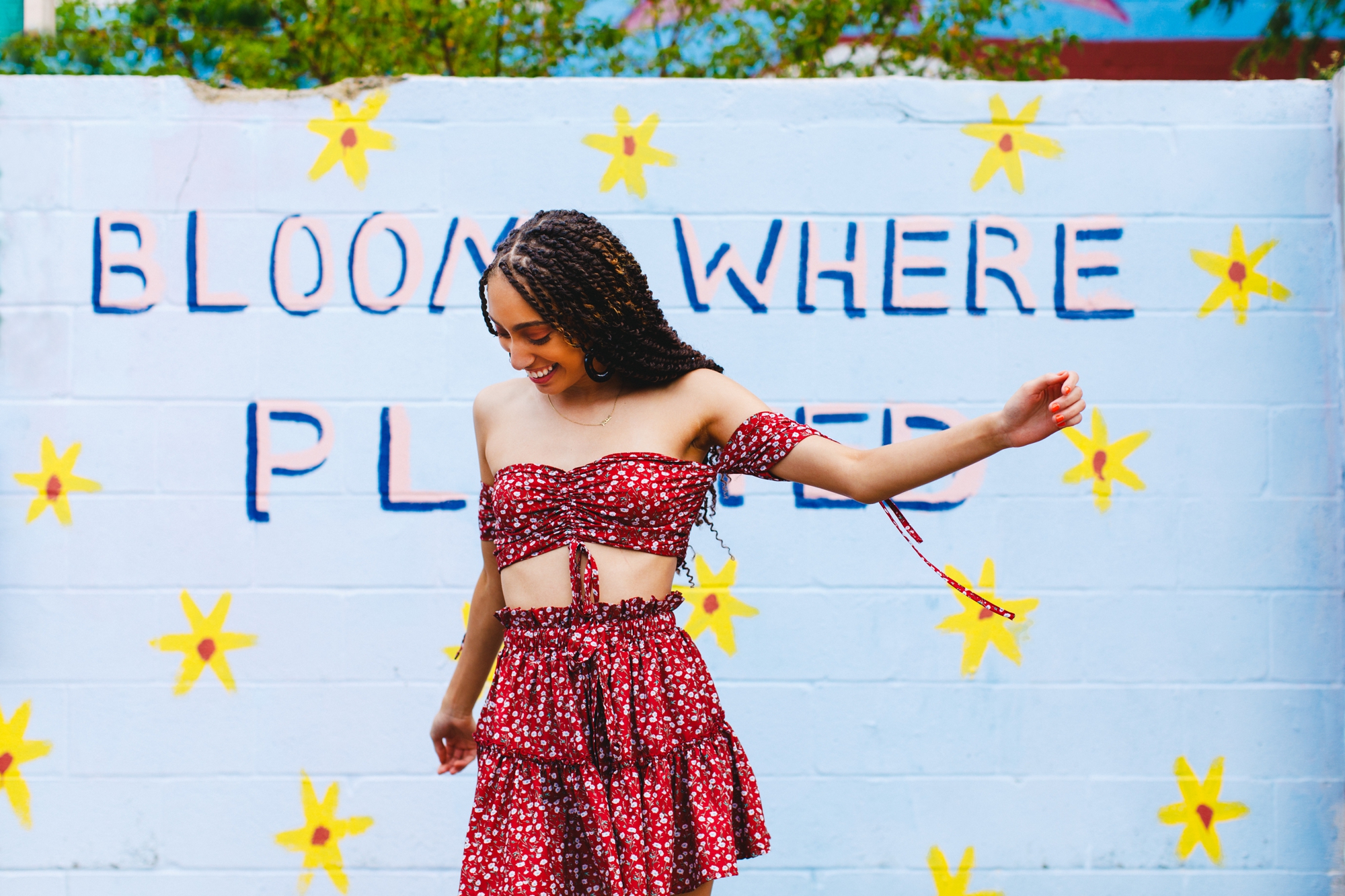 Alize dances in front of a mural that reads "bloom where planted"