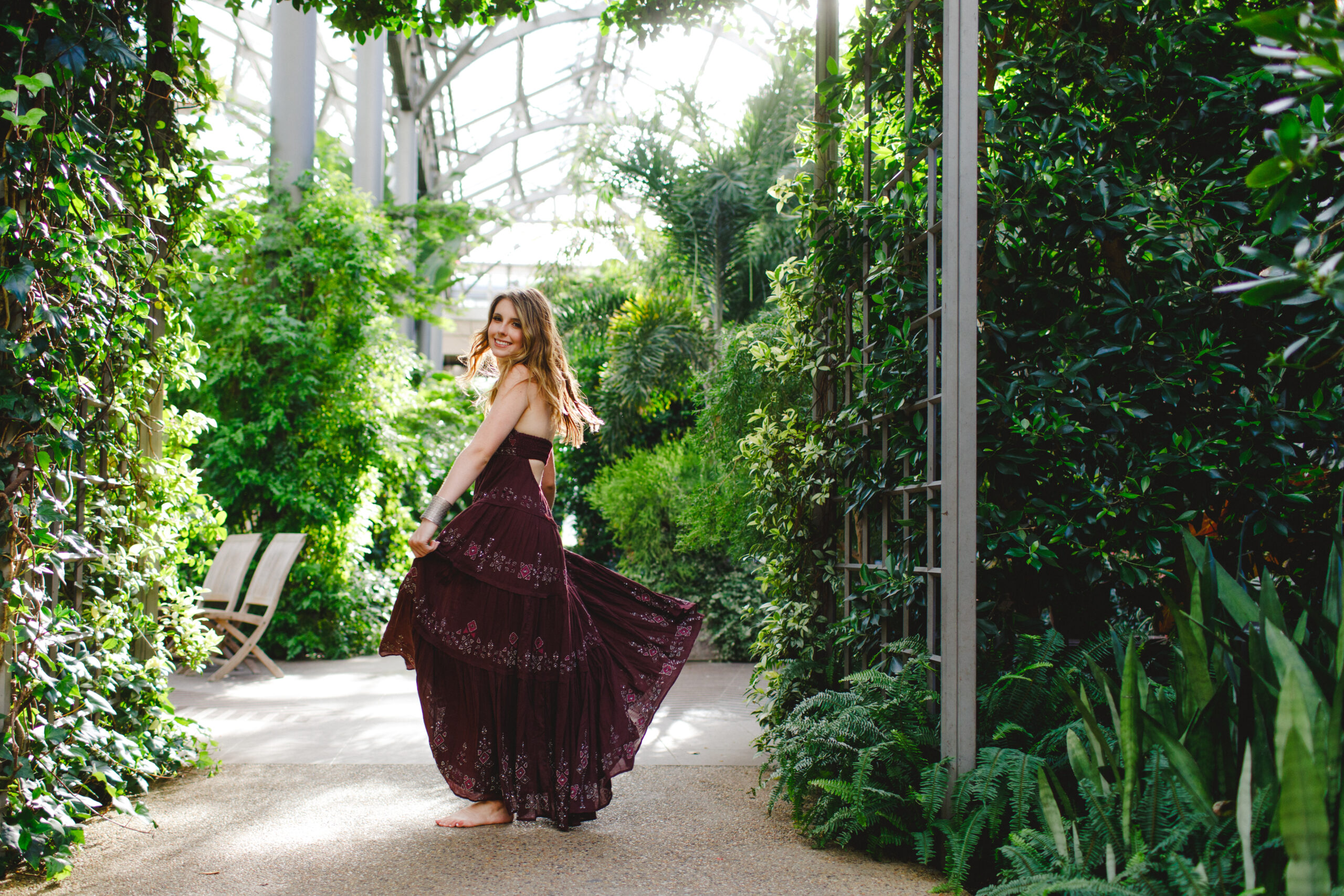 Clare looking over her shoulder as her deep purple beaded dress floats with the breeze in the greenhouse at Longwood gardens.